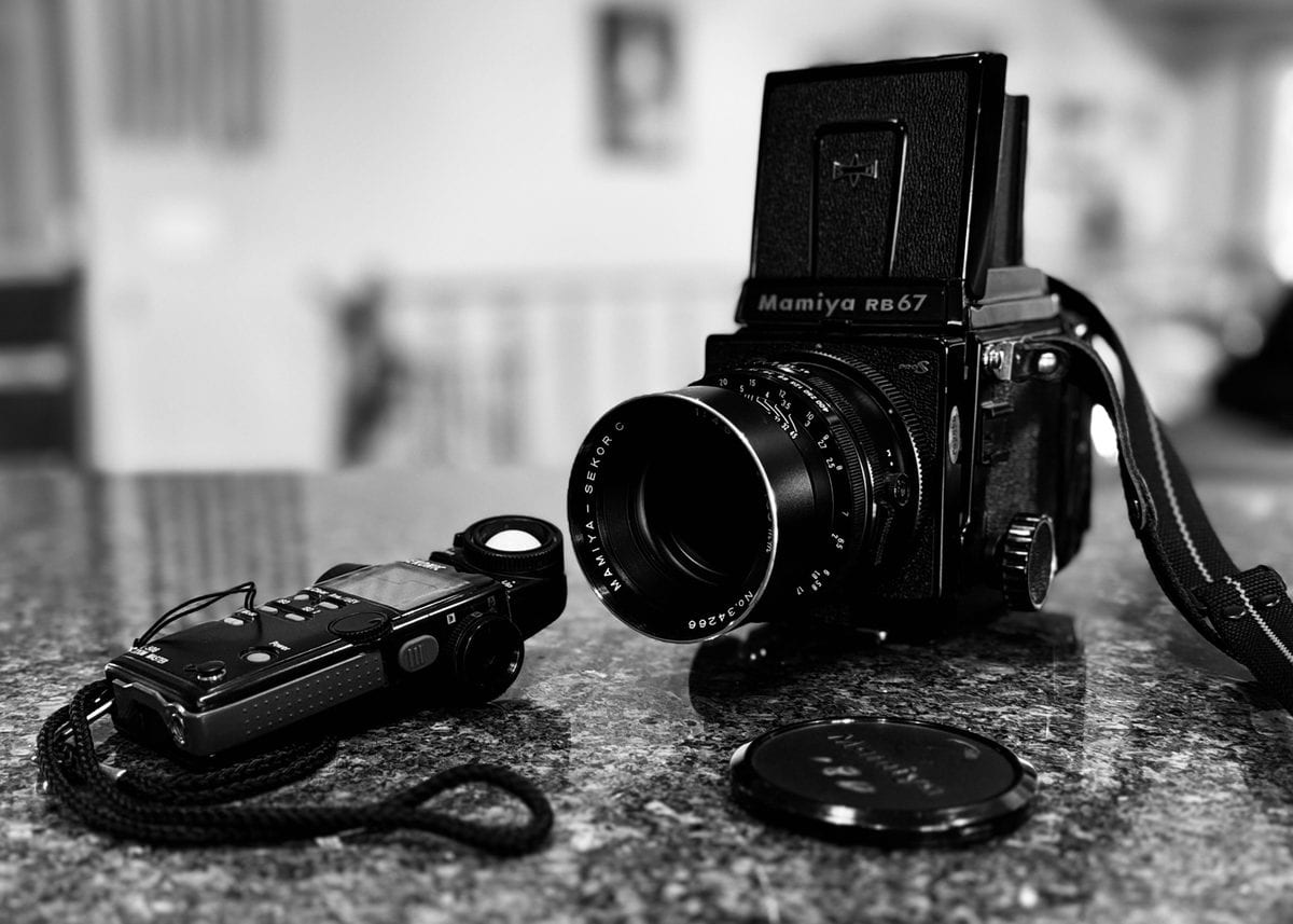 A medium format film camera beside a compact camera