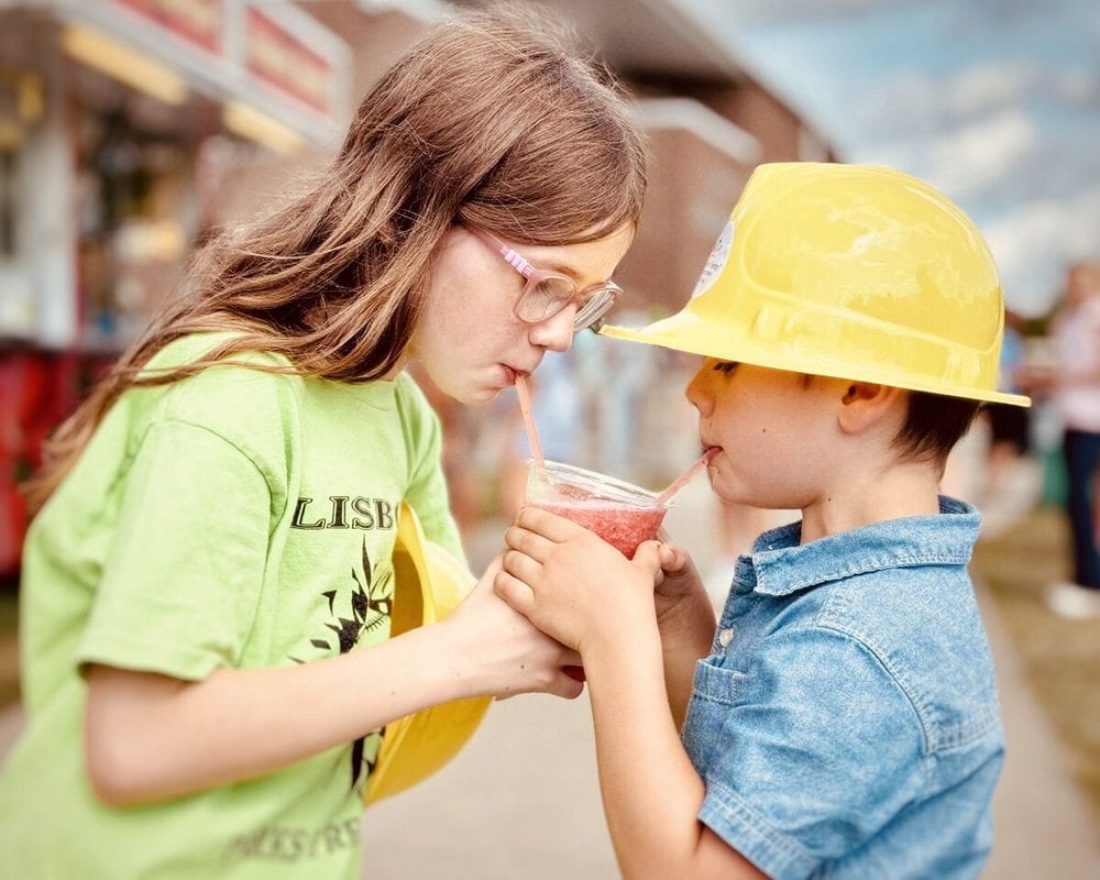 Two kids in sun hats sharing a drink